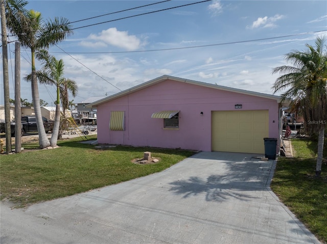 view of side of home featuring a lawn, stucco siding, driveway, and an attached garage