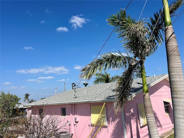 view of side of home featuring stucco siding and roof with shingles