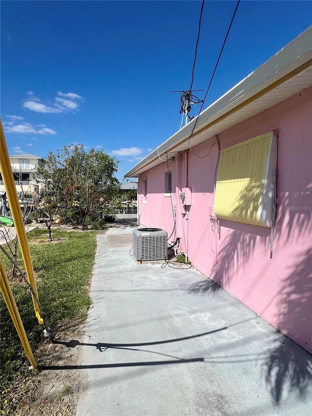 view of side of home featuring stucco siding, central AC, and a patio