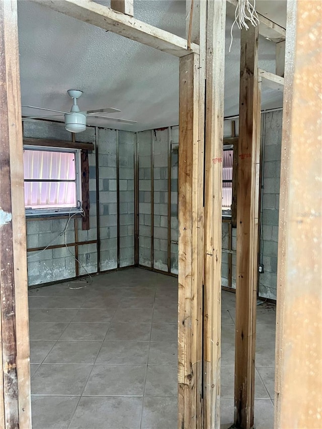 basement with ceiling fan and a textured ceiling