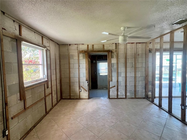 empty room with a textured ceiling, ceiling fan, and light tile patterned floors