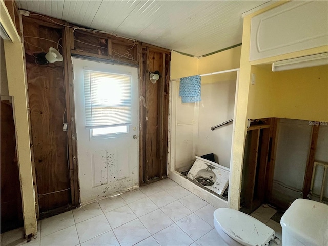 bathroom with toilet, tile patterned flooring, and a shower stall