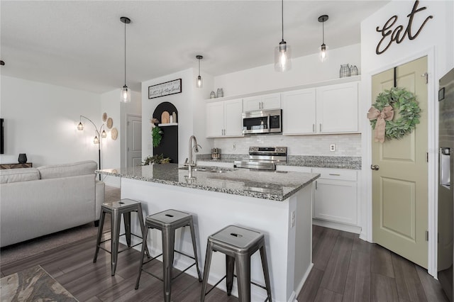 10464 Ladybug Cv, Parrish, FL 34219 - kitchen featuring stainless steel appliances, a sink, open floor plan, a kitchen bar, and tasteful backsplash