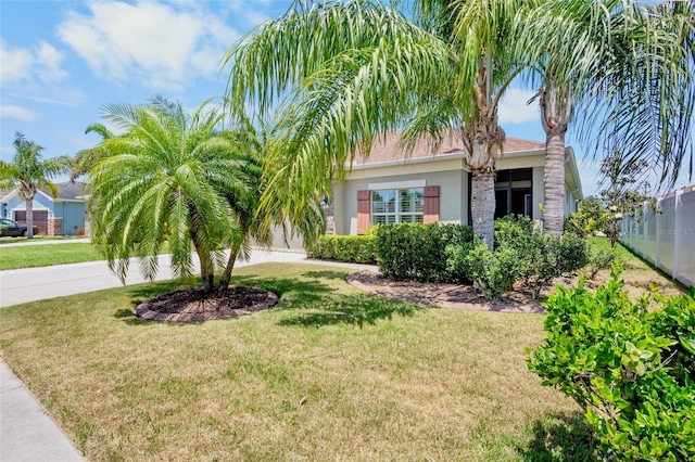view of property hidden behind natural elements with concrete driveway, a front yard, and stucco siding