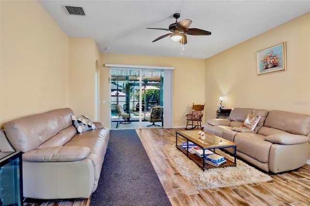 living area featuring a ceiling fan, visible vents, and wood finished floors