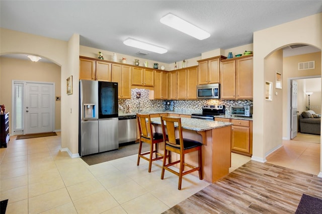 kitchen with tasteful backsplash, visible vents, stainless steel appliances, and arched walkways