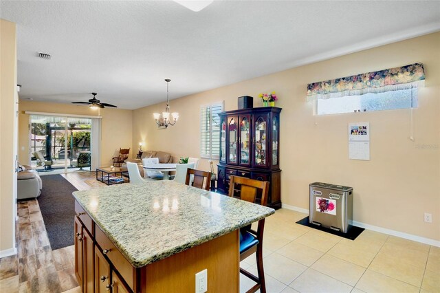 kitchen featuring brown cabinets, a kitchen bar, visible vents, baseboards, and open floor plan