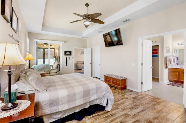 bedroom featuring baseboards, visible vents, connected bathroom, and a tray ceiling