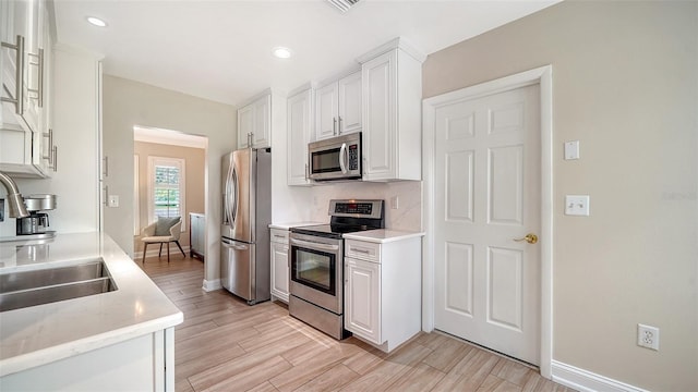 4861 Waterbridge Down, Sarasota, FL 34235 - kitchen with appliances with stainless steel finishes, white cabinetry, light wood-style floors, tasteful backsplash, and recessed lighting