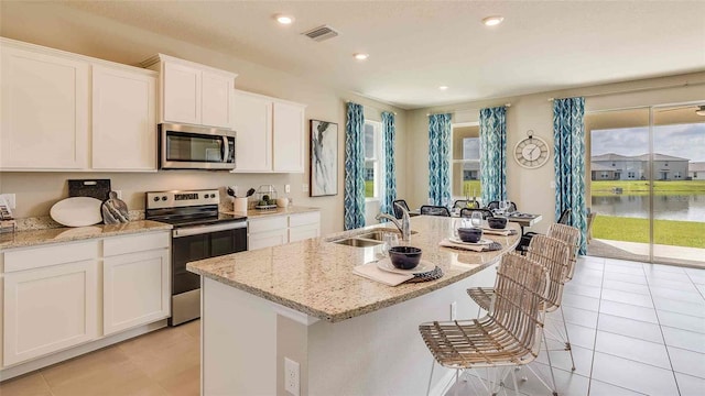 kitchen featuring a sink, light tile patterned floors, stainless steel appliances, white cabinetry, and visible vents