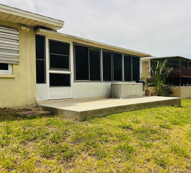 rear view of house with a yard, a patio area, and stucco siding