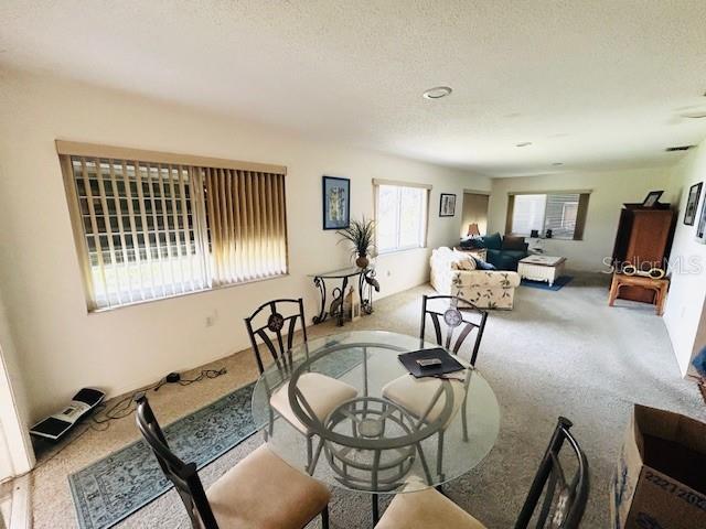 carpeted dining area with a textured ceiling
