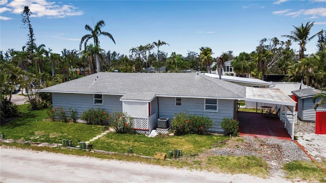 7030 Lois Ave, Longboat Key, FL 34228 - view of front of house with driveway, central AC unit, roof with shingles, a front lawn, and a carport