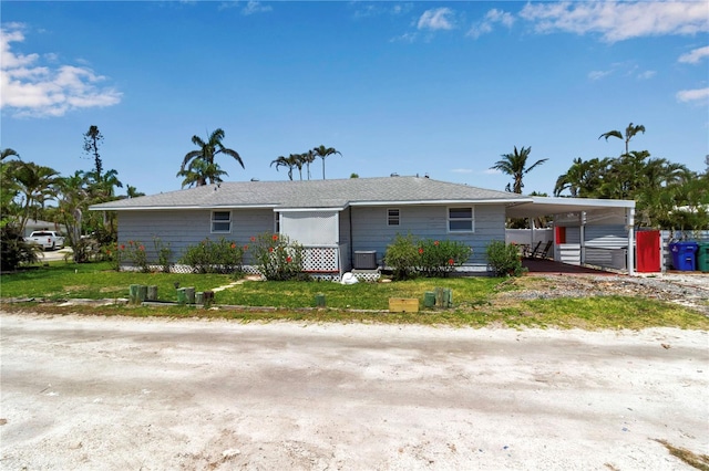 7030 Lois Ave, Longboat Key, FL 34228 - view of front of home featuring central air condition unit, a front lawn, and a carport