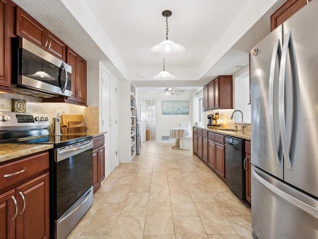 kitchen with a sink, stainless steel appliances, a ceiling fan, decorative light fixtures, and backsplash