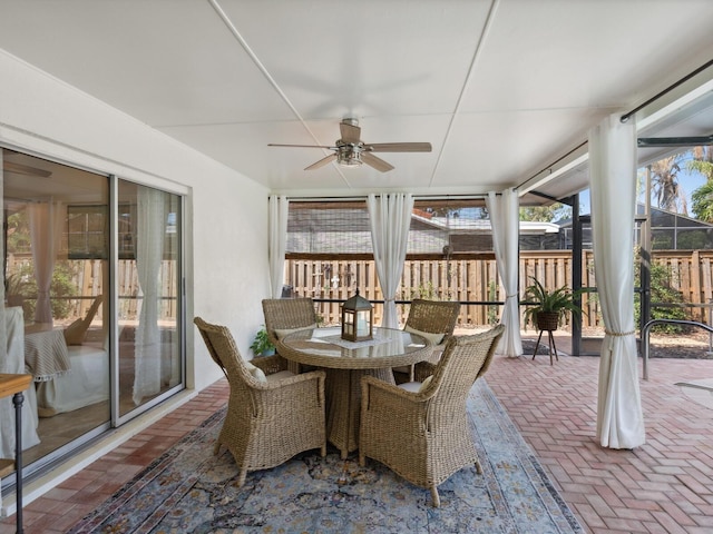 sunroom / solarium with a ceiling fan, brick floor, and outdoor dining space