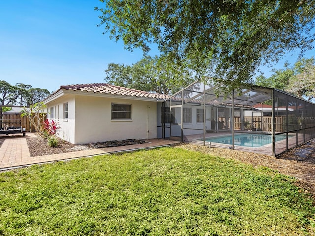 back of property featuring stucco siding, a tiled roof, fence, a fenced in pool, and a lawn