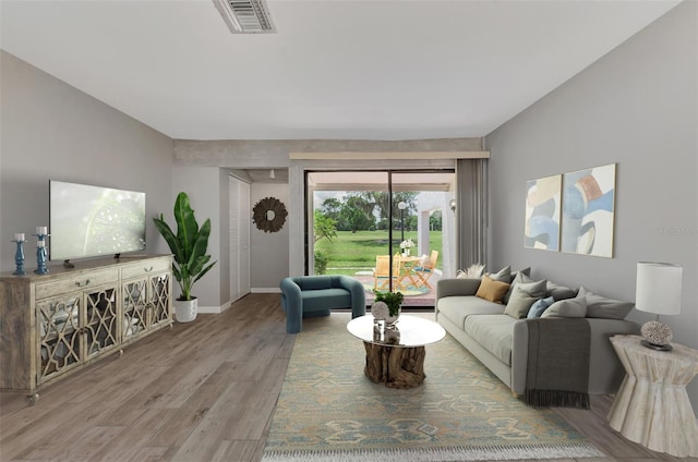 living room with wood finished floors, visible vents, and baseboards