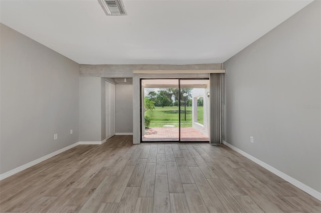 empty room with visible vents, light wood-type flooring, and baseboards