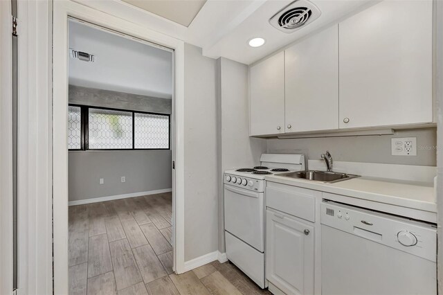 kitchen featuring a sink, visible vents, baseboards, and white appliances
