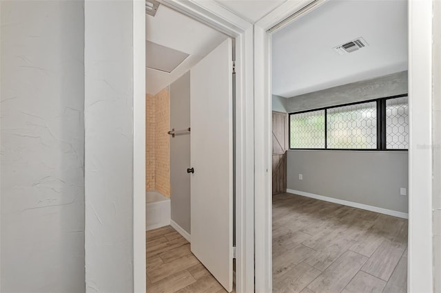 hallway with baseboards, visible vents, and light wood-style flooring
