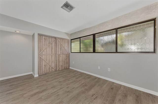 unfurnished bedroom with visible vents, wood finished floors, and baseboards