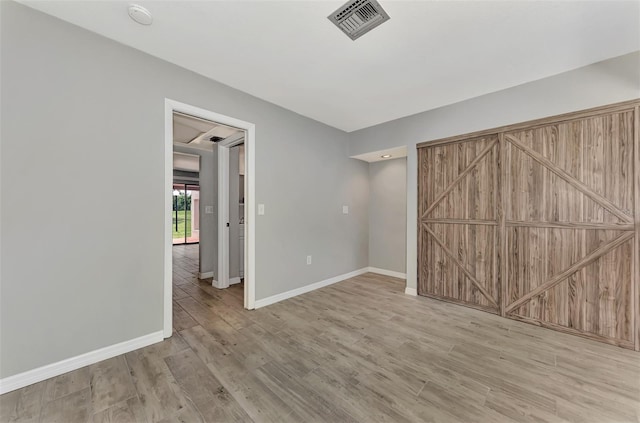unfurnished bedroom featuring visible vents, wood finished floors, and baseboards