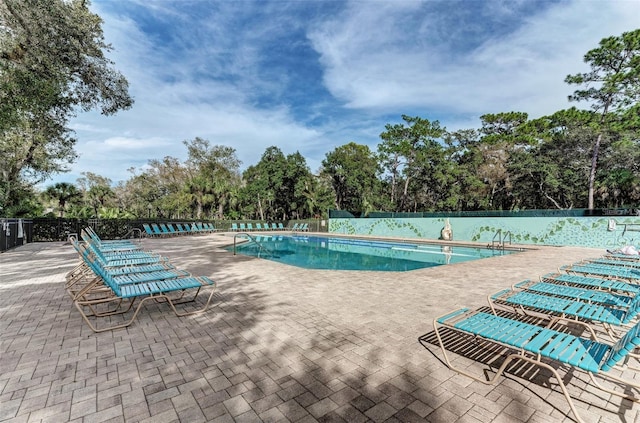 community pool featuring fence and a patio area