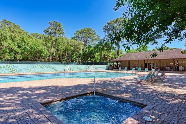 pool with a hot tub, a patio area, and fence