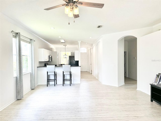 14315 Tree Swallow Way, Lakewood Ranch, FL 34202 - kitchen with arched walkways, appliances with stainless steel finishes, dark countertops, a ceiling fan, and white cabinetry
