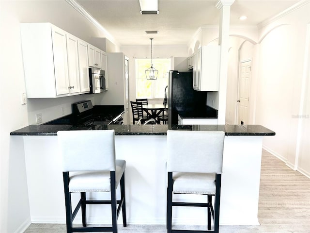 14315 Tree Swallow Way, Lakewood Ranch, FL 34202 - kitchen with appliances with stainless steel finishes, crown molding, white cabinets, a peninsula, and a breakfast bar