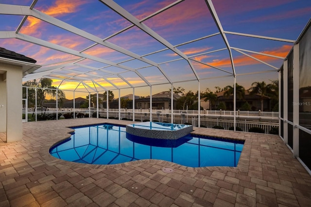 569 Mast Dr, Bradenton, FL 34208 - pool at dusk featuring a patio area, a pool with connected hot tub, glass enclosure, and a fenced backyard