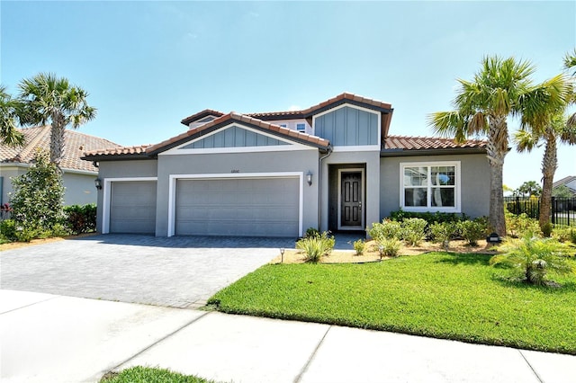 view of front facade featuring a front lawn, decorative driveway, stucco siding, an attached garage, and a tile roof
