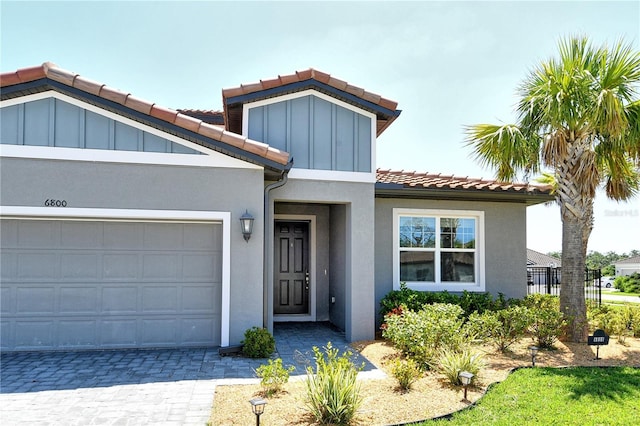 view of front of home with a garage, a tiled roof, decorative driveway, and stucco siding