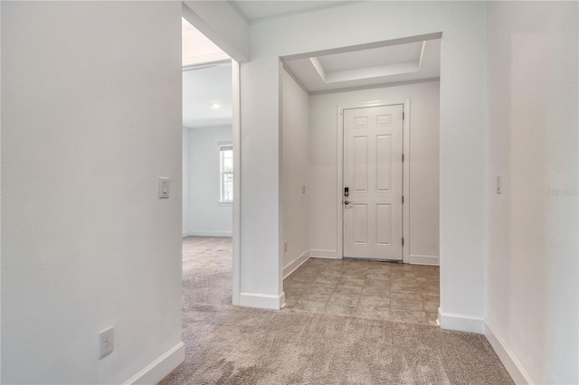 entrance foyer with carpet floors, baseboards, and a tray ceiling