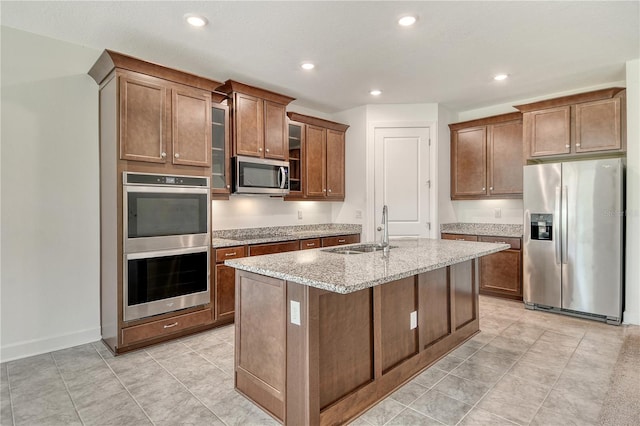 kitchen featuring a sink, light stone counters, stainless steel appliances, and recessed lighting