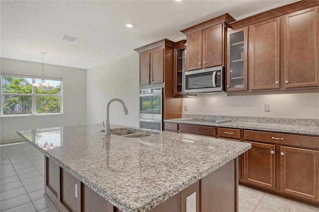 kitchen featuring light stone countertops, a sink, glass insert cabinets, stainless steel appliances, and light tile patterned flooring