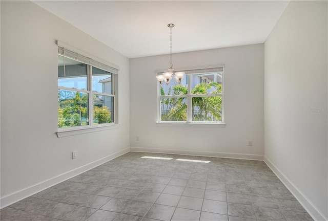 empty room featuring an inviting chandelier, baseboards, and light tile patterned floors