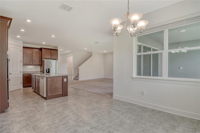kitchen featuring visible vents, a kitchen island with sink, open floor plan, recessed lighting, and stainless steel fridge