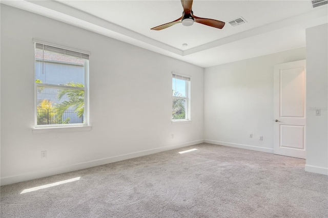 carpeted spare room featuring baseboards, a ceiling fan, a raised ceiling, and visible vents