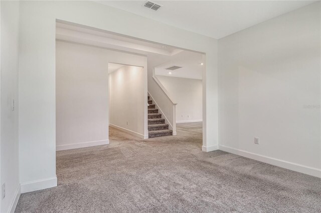 empty room featuring carpet floors, baseboards, stairs, and visible vents