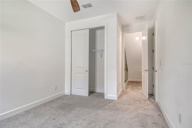 unfurnished bedroom featuring a closet, baseboards, light colored carpet, and visible vents