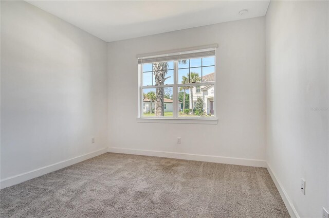 carpeted empty room featuring baseboards