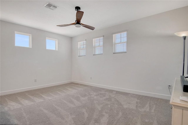 spare room featuring light colored carpet, baseboards, and a healthy amount of sunlight