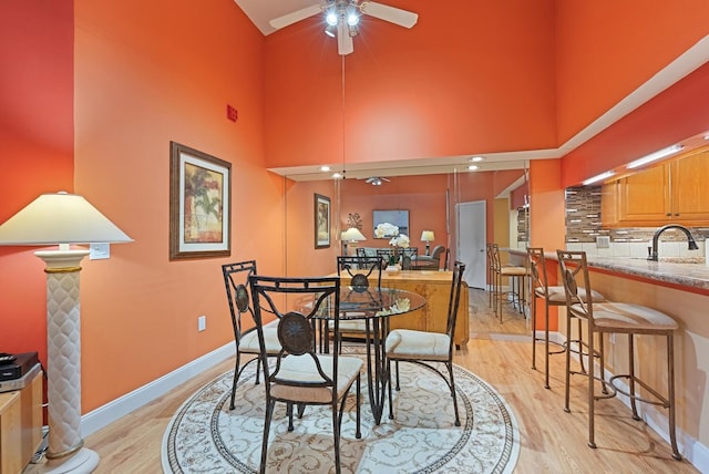 5736 Ashton Lake Dr, Sarasota, FL 34231 - dining area with a ceiling fan, light wood-style flooring, a towering ceiling, baseboards, and ornate columns