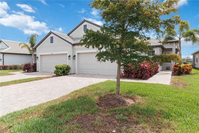 view of front of home with decorative driveway, stucco siding, a front yard, an attached garage, and a tiled roof