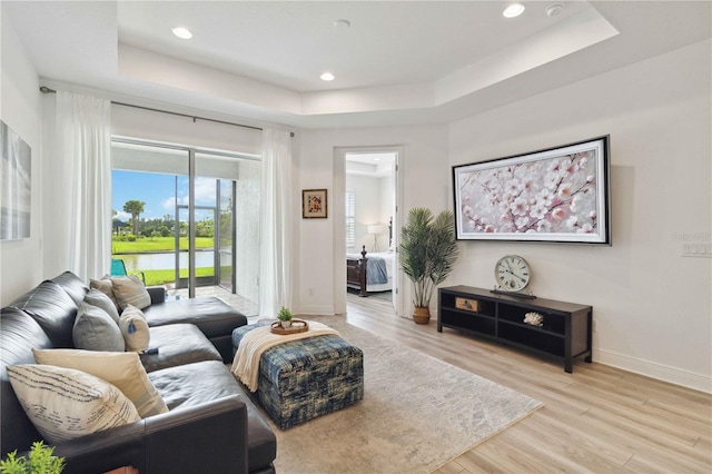 living room featuring a raised ceiling, wood finished floors, baseboards, and recessed lighting
