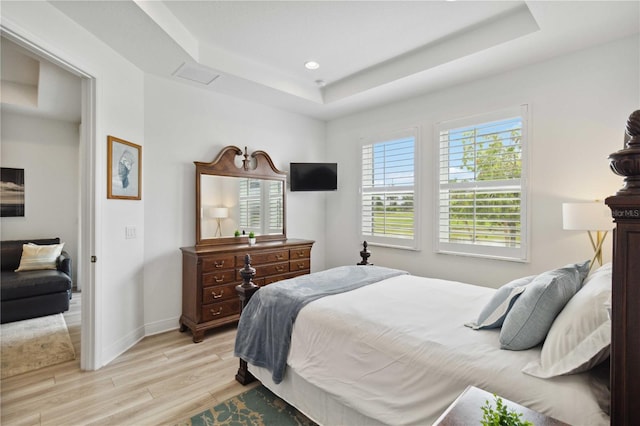 bedroom with a tray ceiling, light wood-style flooring, baseboards, and recessed lighting