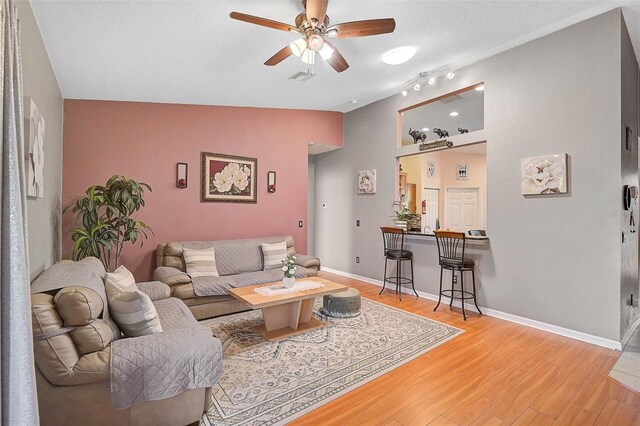 1789 Elm Dr, Venice, FL 34293 - living room with lofted ceiling, a textured ceiling, light wood-style flooring, baseboards, and a ceiling fan