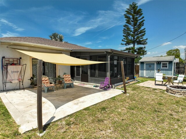 1789 Elm Dr, Venice, FL 34293 - back of house featuring an outdoor structure, a yard, a fire pit, a patio, and a sunroom